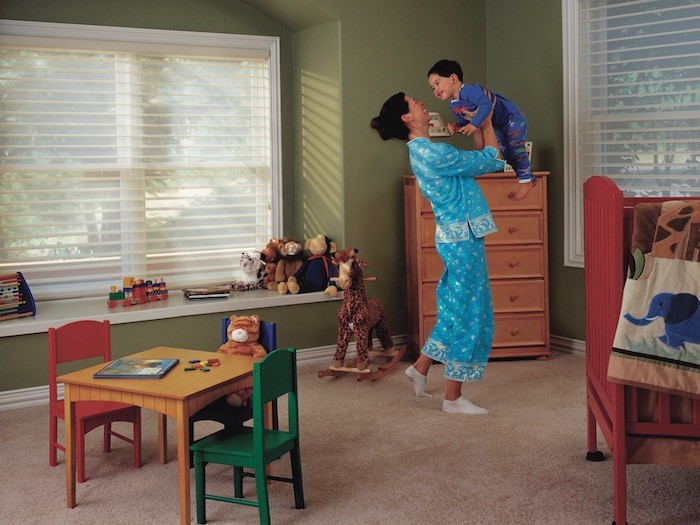 Mother holding son in pajamas in toy room.